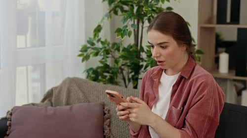 Woman Looks at Phone and Reacts with Joy