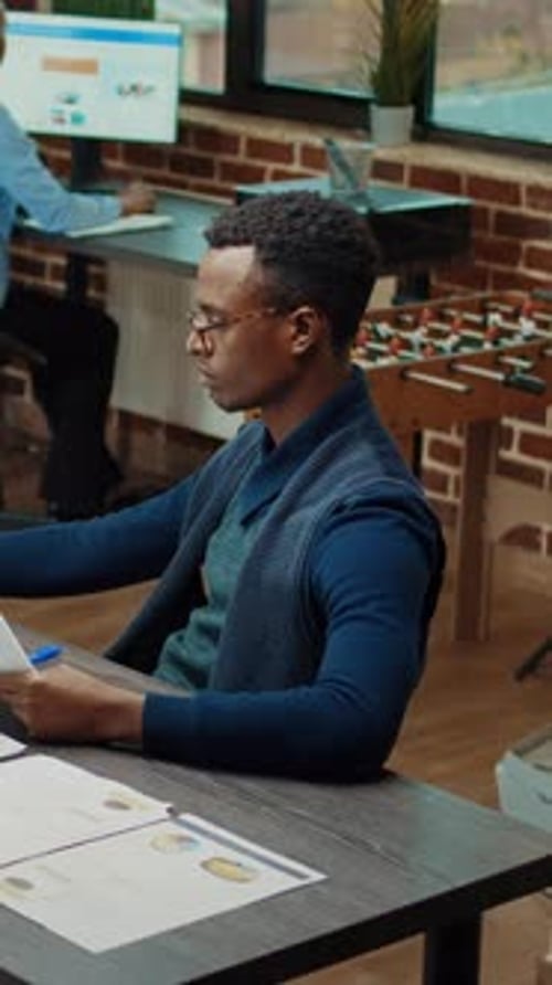 Young Adult Reviews Documents at Work Desk