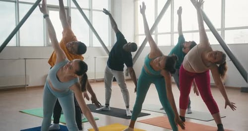 Yoga Class Stretching in a Bright, Spacious Studio