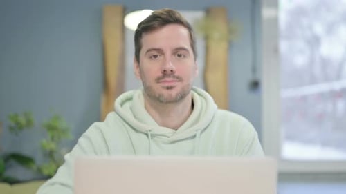 Close Up of Thumbs Up by Young Man Working on Laptop
