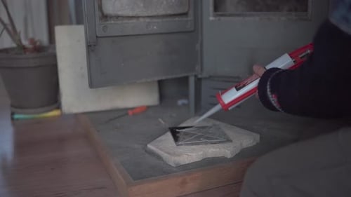 Person Caulking Decorative Tiles in Front of Stove