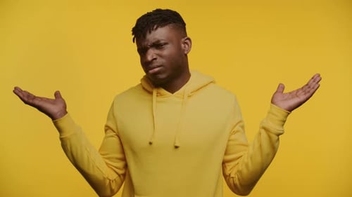 Man Shrugging in Confusion on Yellow Background