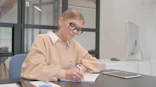 Female Worker Writing a Letter in Office