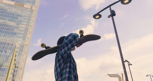 Portrait a boy practices skateboarding in the middle of the city, between buildings and skyscraper