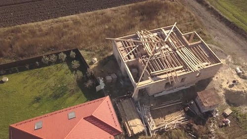 Top Down Aerial View of Two Private Houses One Under Construction with Wooden Roofing Frame and
