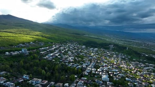 Aerial View of City at the Foot of Green Mountains