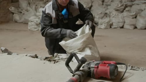 Construction Worker Fills Bag with Debris