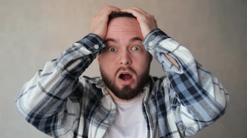 Man Reacts with Surprise and Shock, Grabbing Head