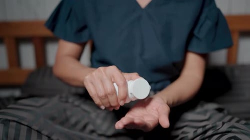 Pills Pouring From a White Bottle onto Hand