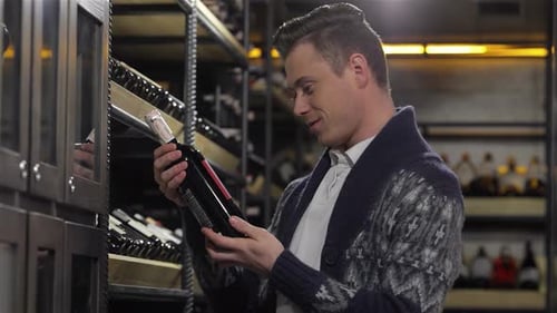 Charming Young Man Examining a Bottle of Wine
