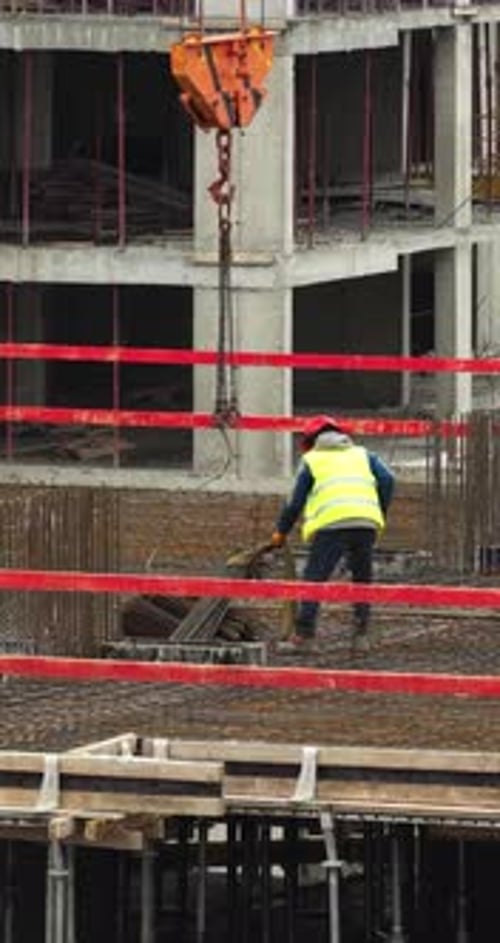 Vertical Aerial Drone Shot of Construction Worker Receiving Crane Load With Steel Rebar