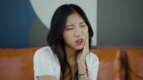 Upset young asian woman touch cheek, suffers from toothache, girl having terrible sudden tooth pain