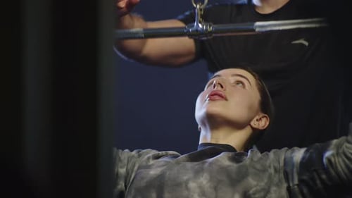 A Woman Works Out on an Exercise Machine in a Gym with a Trainer
