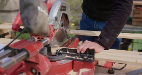 Man Cutting Wood with Miter Saw Outdoors