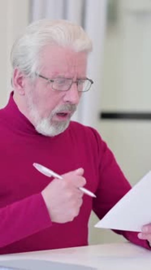 Senior Man Reviewing Documents with Upset Expression