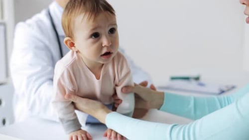 Doctor Examines Baby with Mother at Clinic