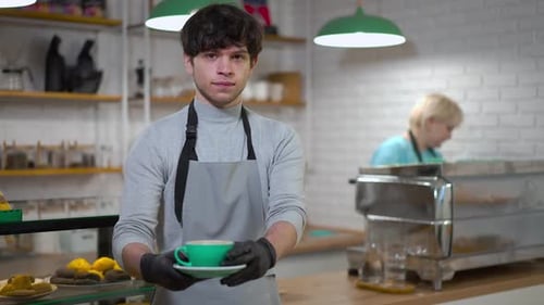 Friendly Barista Serving Latte in Busy Coffee Shop