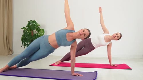 Women Perform Side Plank Yoga Pose in Studio