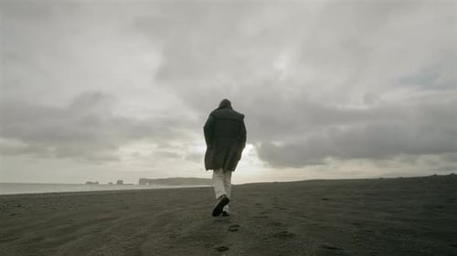 A Young Man Walking Along the Stunning Reynisfjara Black Sand Beach in Beautiful Iceland