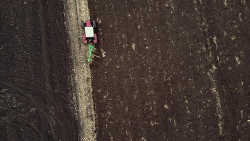Red tractor plowing the field in Ukraine