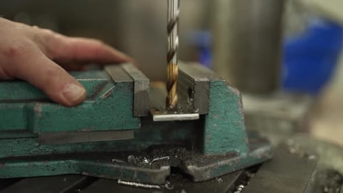 Der Bohrer durchschneidet mit einem Schraubstock eine Metallplatte, präzise in einer Industriewerkstatt