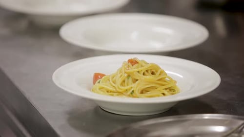 Close-up of spaghetti pasta with tomatoes and basil in a white bowl on a kitchen counter
