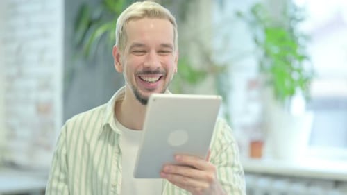 Jeune homme moderne faisant un chat vidéo en ligne via une tablette