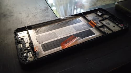 Closeup hand held view of smartphone opened, microchip details of broken phone fixing process