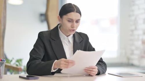 Young Woman Looking at Documents in Office