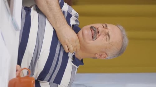 Vertical video of Home office worker old man suffering from sore throat.