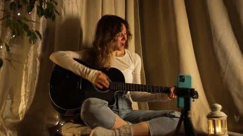 Woman Sings and Plays Guitar by Warm Light