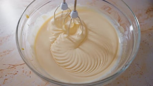 Closeup of mixer or food processor mixing mascarpone cream in a glass bowl. The Process Of Making Ta