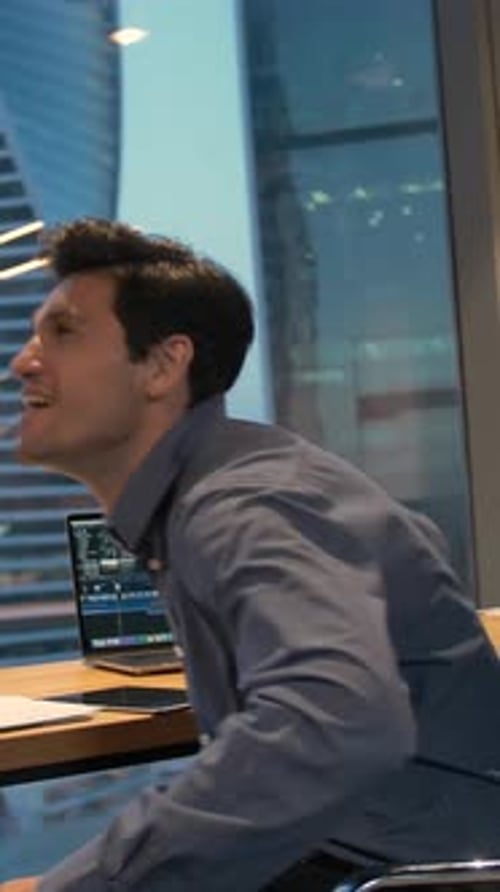 Man Celebrates Success in Modern Urban Office at Night