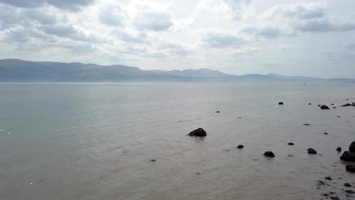 Strange creepy Martian mountain range rocky alien stone beach ocean rising shot reverse