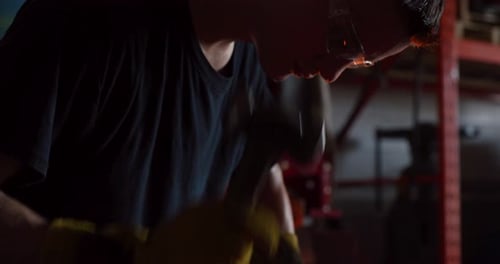 Blacksmith Shaping Hot Metal with Hammer at Anvil