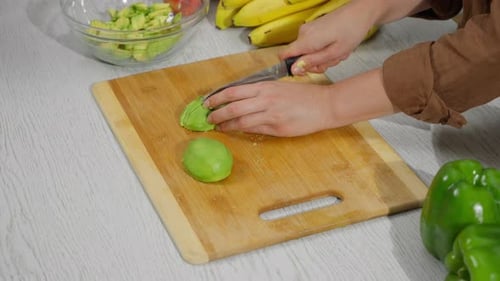 Chopping green bell peppers in a kitchen setting