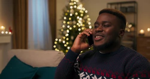 Young Adult Talking on the Phone near Christmas Tree