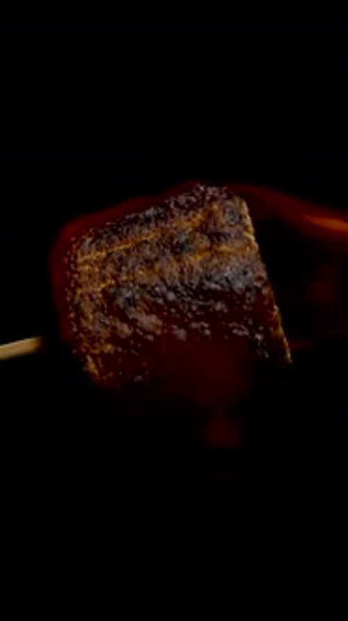 Vertical video. Burnt Marshmallow Rotating Slowly with Intense Flame Glow on Black Background, close