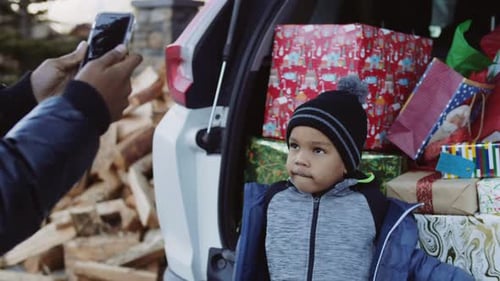 Little Boy With Holiday Presents at Car Trunk