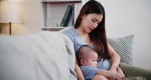 Young Woman Holding Baby on Couch