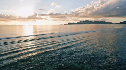 Tranquil Ocean Waves Gently Roll onto a Beach at Sunset