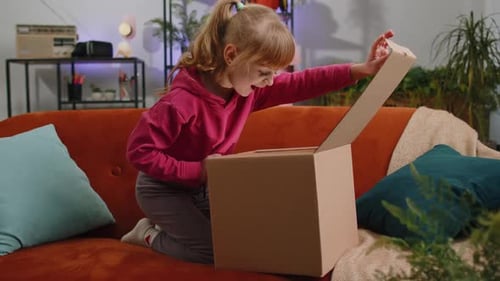 Happy Child Girl Shopper Unpacking Cardboard Box Delivery Parcel Online Shopping Purchase at Home