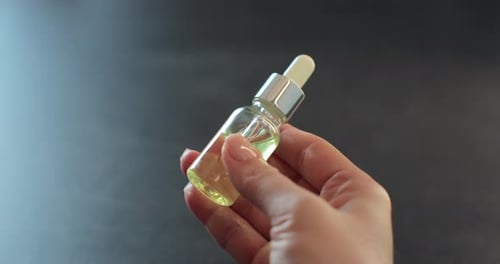 Hand Holding Small Bottle of Facial Serum