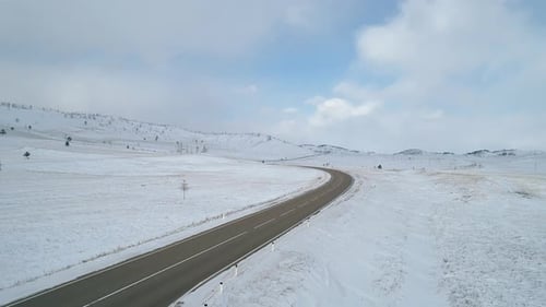 Aerial Landscape Intercity Road in Rural Area Road Surrounded with Snowy Fields and Hills Against