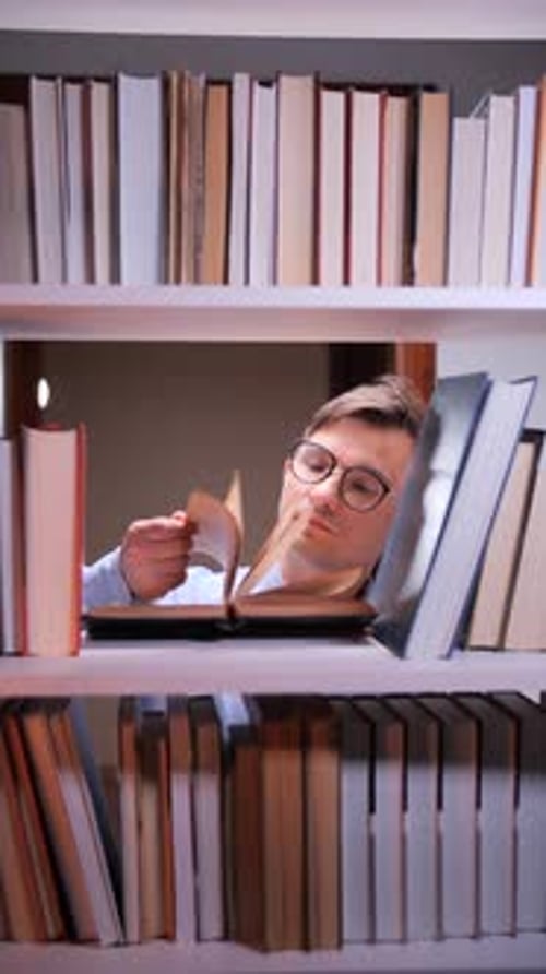 Vertical Video Researcher Reading Book on Bookshelf in Library at Night