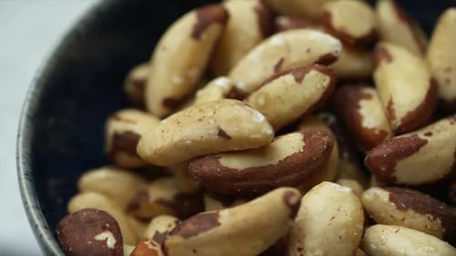 Brazil nuts rotating in blue bowl. Wholefood Brazil nut image of raw foods. Shallow depth of field H