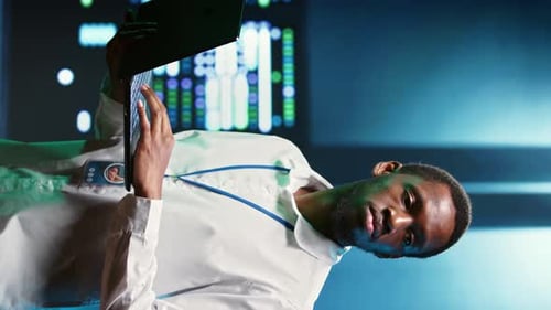 Man Typing on Laptop in Blue-Tinted Lab