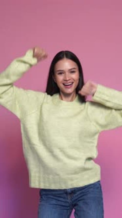 Smiling Woman Dancing Joyfully Against a Pink Background