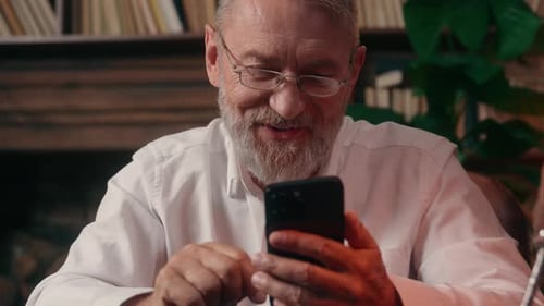 Senior Man Using Phone in Home Library