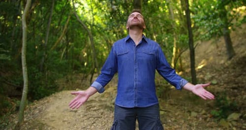 Super slow motion of young man breathe and enjoy a green forest with the raised arms in 4k (close